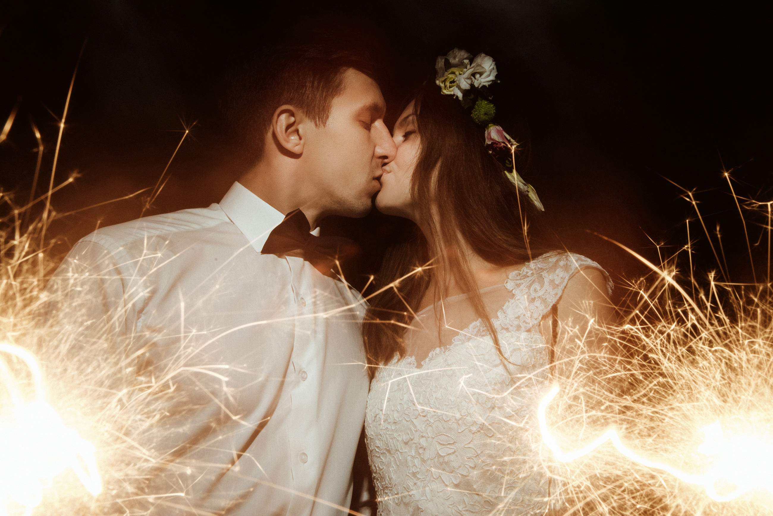 happy beautiful bride and elegant stylish groom holding fireworks on the top of a mountains in the evening