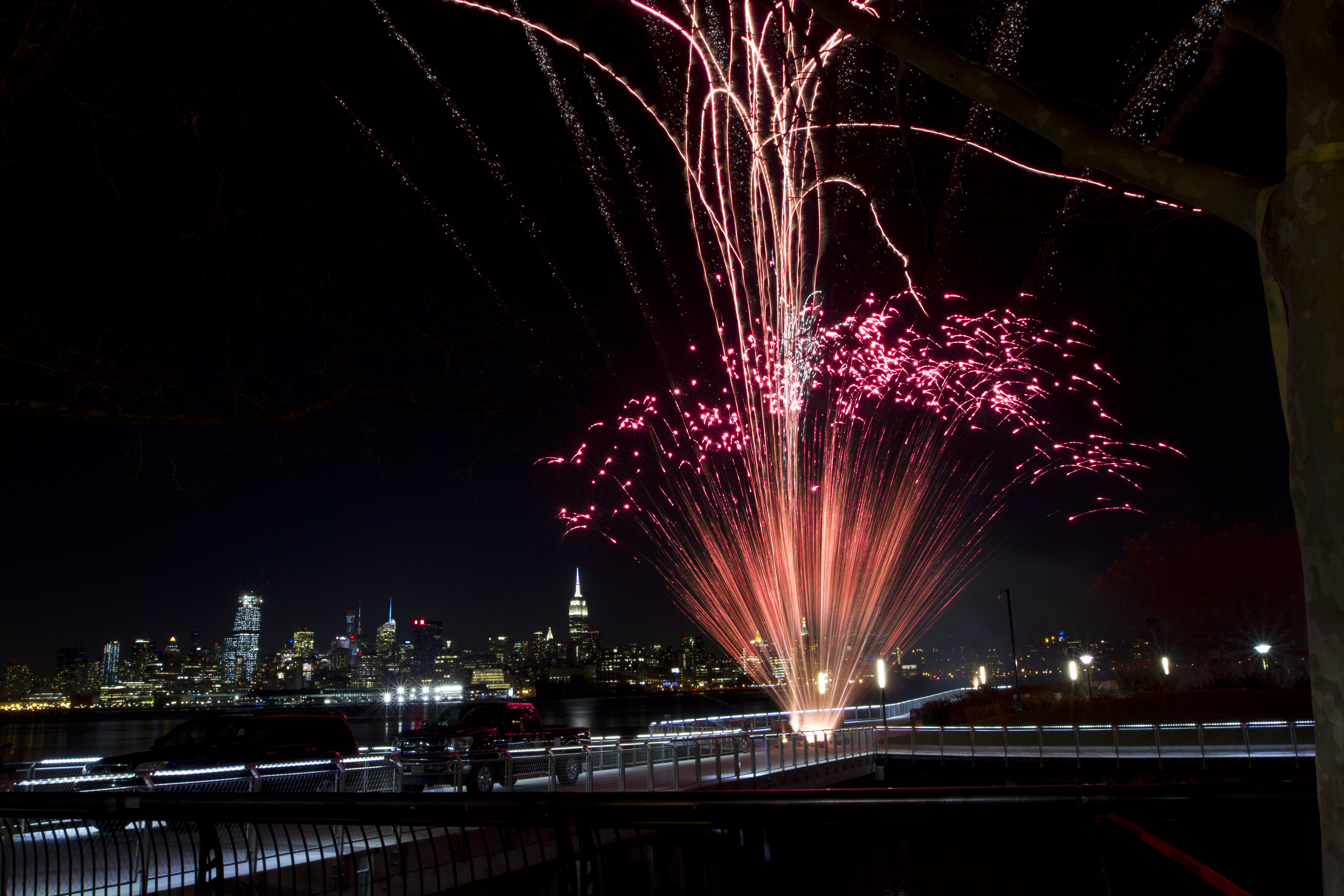 A beautiful red fan cake ignited over the Hudson River during a NJ wedding fireworks show set up by a fireworks company.