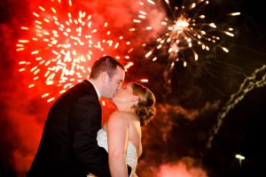 A NJ Wedding Fireworks display with a bride and groom kissing and fireworks going off in the background.