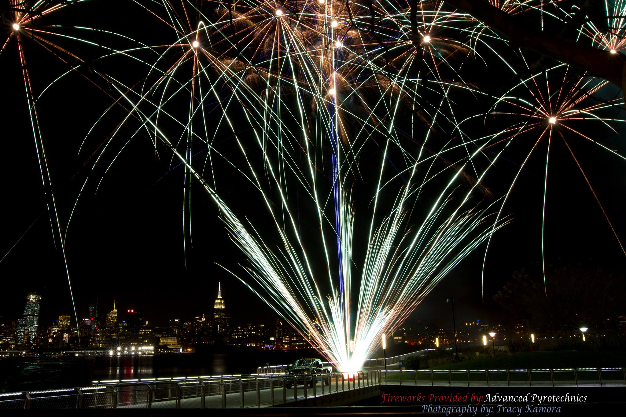 A silver fan cake ignites with New York City in the background during a NJ wedding fireworks show.